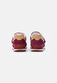 Sneakers in suede rosso con accenti bianchi e beige, dotati di una suola in gomma testurizzata, colletto imbottito e dettagli con logo sul tallone.