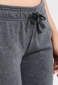 Grijze sweatpants gemaakt van zachte stof met een elastische tailleband, voorzien van een trekkoord en een gladde, aansluitende pasvorm.