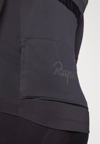 Crna biciklistička majica sa teksturiranim dizajnom, donjim džepom sa patentnim zatvaračem i logotipom "Rapha". Izrađena je od rastezljivog, laganog materijala.