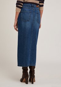 Falda midi de mezclilla en azul oscuro con un corte recto, dos bolsillos traseros y un sutil detalle en la cinturilla. La textura es suave con un acabado clásico.