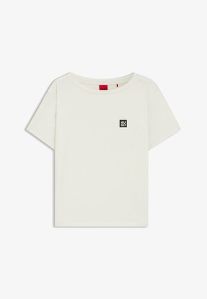 Vit bomullströja med rund hals och korta ärmar. Har en liten svart fyrkantig logotyp med "HUGO" på vänster bröstområde.