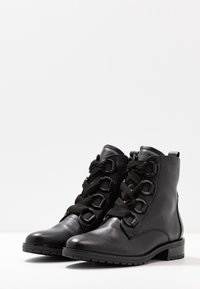 Bottines en cuir noir avec bout rond, surface texturée, lacets décoratifs avec quincaillerie en métal et un petit talon carré.