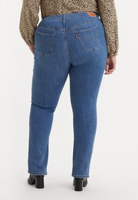 Jeans skinny in denim blu scuro con vita alta, tasche posteriori con archi cuciti e patch in pelle a contrasto sul retro.