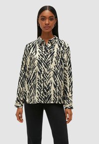 Blusa a maniche lunghe color crema con motivo astratto nero, colletto con bottoni, vestibilità rilassata e tessuto morbido e leggero.