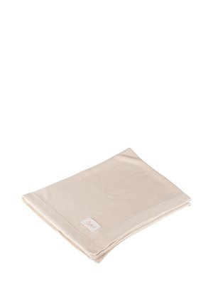 Light beige folded knit blanket with a small white tag on a white background.