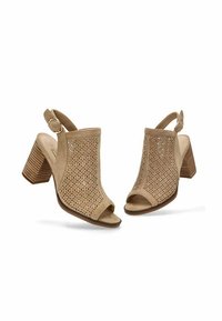 Sandalias de tacón alto de ante beige con diseño floral perforado, punta abierta y correa de tobillo ajustable. Tacón cuadrado con rayas verticales.
