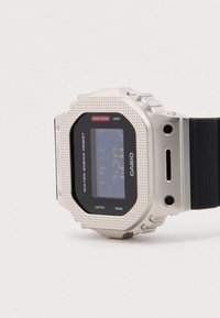 Ψηφιακό ρολόι Casio με μεταλλική ασημί κάσα, μαύρη οθόνη LCD, ανάγλυφη στεφάνη και μαύρο λουράκι σιλικόνης. Αδιάβροχο έως 20 bar.