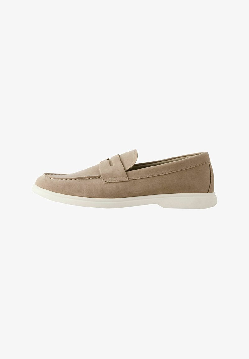 Mocassin en daim beige avec semelle blanche, bout arrondi et détails cousus, conçu pour un port décontracté ou semi-formel, présenté en profil latéral.