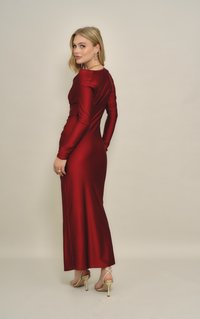 Μακρύ κόκκινο σατέν φόρεμα με εφαρμοστή μπούστα και μακριά μανίκια, λεία υφή και φαρδύ τελείωμα, σετάρισμένο με χρυσά ψηλοτάκουνα με λουράκια.