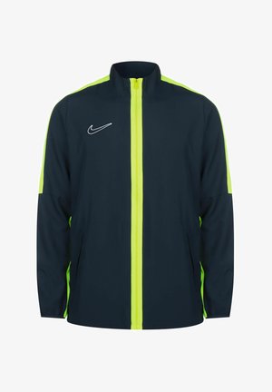 Nike windbreaker jacket in navy with neon yellow accents. Features a full front zip, high collar, and side pockets. Smooth fabric texture.