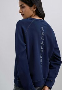 Marine sweatshirts mit gerippten Bündchen, mit geprägtem "SCALPERS"-Text auf der Rückseite. Weiches Material mit lässiger Passform und Raglanärmeln.