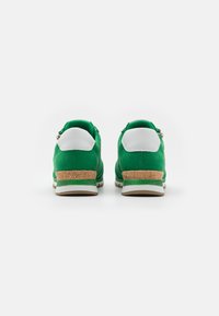 Baskets en suede vert avec des accents de talon blancs et un détail en liège à l'arrière. Comprend une semelle texturée et une semelle intermédiaire blanche contrastante.