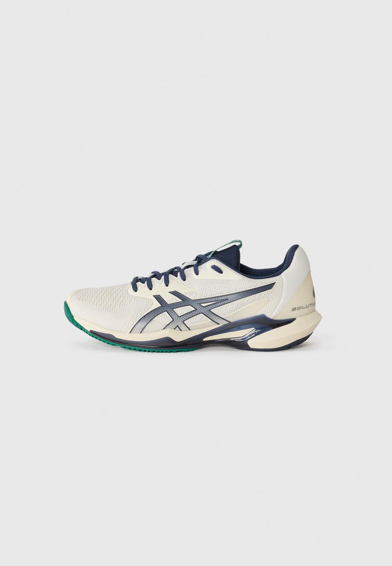 Lightweight running shoe in cream with dark blue accents. Mesh upper, sleek design, green rubber outsole, and reflective detailing.