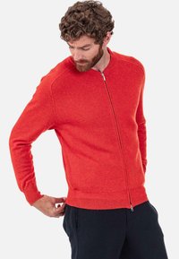 Roter Cardigan mit Reißverschluss aus strukturiertem Strickmaterial mit gerippten Bündchen und Saum. Verfügt über einen Stehkragen und eine figurbetonte Passform.