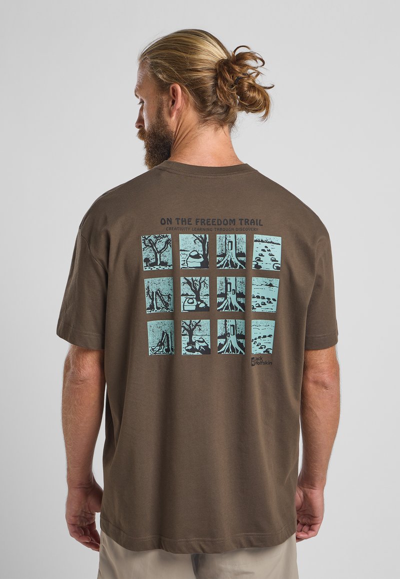 Bruine katoenen t-shirt met een grafiek op de achterkant met negen blauwe vierkanten die natuurtafereeltjes weergeven en de tekst "ON THE FREEDOM TRAIL."
