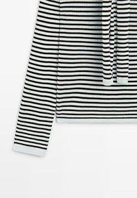 Sort og hvid langærmet bluse med vandrette striber og en rund halsudskæring, lagt fladt mod en hvid baggrund.