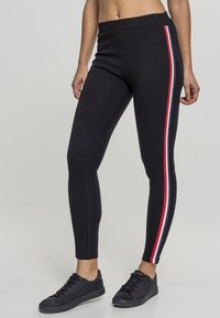 Fekete leggings, testhezálló kialakítással, oldalsó piros és fehér csíkkal. Stretch anyagból készült, aktív viselethez ideális.