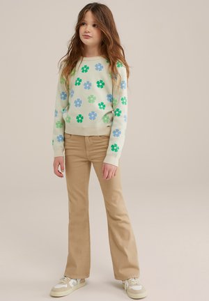 Lys grøn sweater med blå og grønne blomstermønstre, parret med beige buksestil og beige sneakers. Blødt strikmateriale.