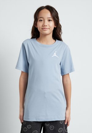 Camiseta de algodón azul claro con cuello redondo y mangas cortas, que presenta un logotipo blanco de Jordan bordado en el lado izquierdo del pecho.