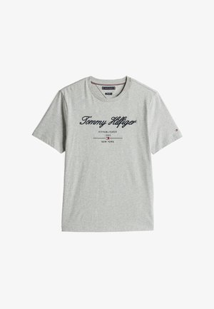 T-shirt en coton gris avec encolure en V, manches courtes, et "Tommy Hilfiger" imprimé en bleu marine. Comprend des détails de marque et la date de création.
