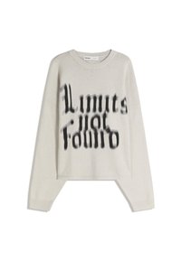 Svetlobežový sveter s dlhým rukávom a čiernym rozmazaným textom "Limits for Edmio" v štýlovom písmene na prednej strane, s rebrovanými manžetami a golierom.