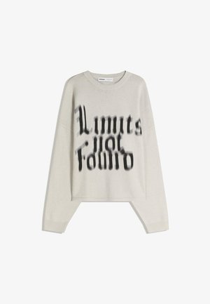 Světle béžový svetr s dlouhým rukávem, na přední straně s černým rozmazaným textem "Limits for Edmio" ve stylizovaném písmu, s žebrovanými manžetami a límcem.