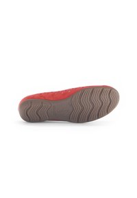 Chaussure en velours rouge avec un design perforé, semelle en caoutchouc présentant un motif ondulé, et logo embossé sur le talon. Vue par le dessous affichée.