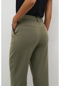 Pantalon vert olive à coupe ajustée, doté de poches latérales et de poches arrière passepoilées, fabriqué en tissu texturé.