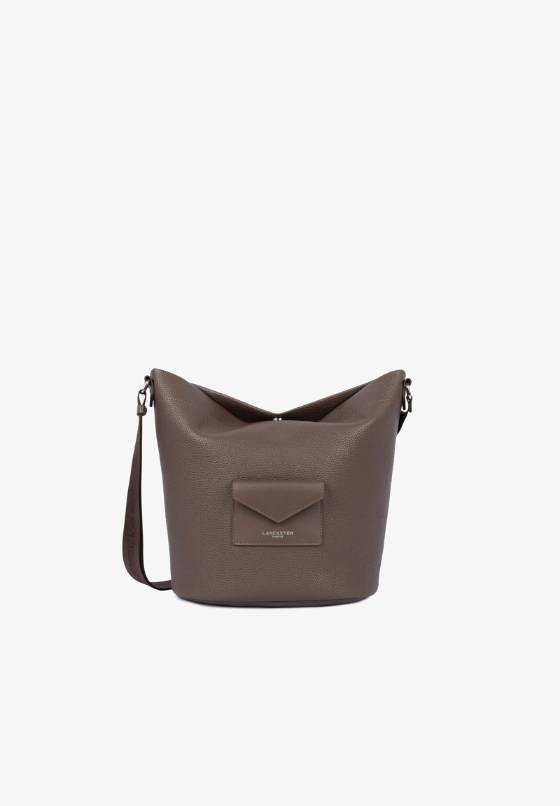 Sac seau en cuir marron texturé avec une bandoulière ajustable et un rabat de poche avant portant l’étiquette Lancaster Paris.