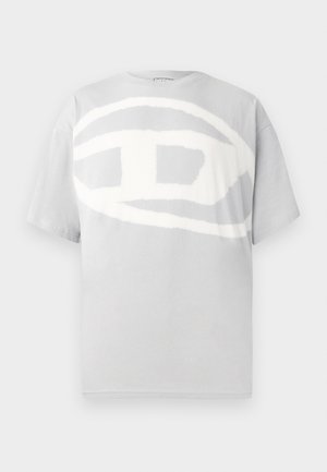 Siva pamučna majica s velikim, apstraktnim bijelim logotipom na prednjoj strani. Kratki rukavi i okrugli izrez. Glatka tekstura.