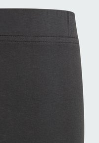 Leggings de un gris oscuro, hechos de un material suave y elástico con una textura lisa. Cuentan con una amplia cinturilla elástica y costuras planas para mayor comodidad.