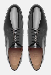 Chaussures habillées en cuir verni noir avec une finition lisse, bout fermé et design à lacets avec des lacets gris et un logo subtilement embossé sur la semelle intérieure.