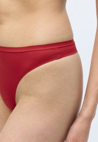 Rode bikini-achtige ondergoed gemaakt van glad, rekbaar materiaal; heeft een effen ontwerp en een tonale tailleband met "Calvin Klein" branding.