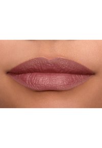 Matowa pomadka w stonowanym odcieniu mauve, charakteryzująca się gładką teksturą i wyraźnie zarysowanymi konturami, wyeksponowana na naturalnym tle ust.