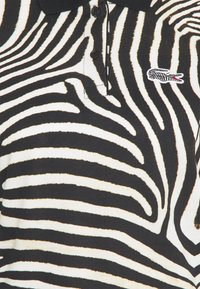 Czarna i biała paskowana koszulka polo z klasycznym kołnierzykiem, plisą na trzy guziki oraz małym haftowanym logo na piersi.