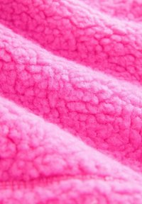 Fleece stof in een heldere roze kleur, met een gestructureerd, pluizig oppervlak dat een zachte, harige uitstraling heeft en oneven, bubbelachtige patronen.