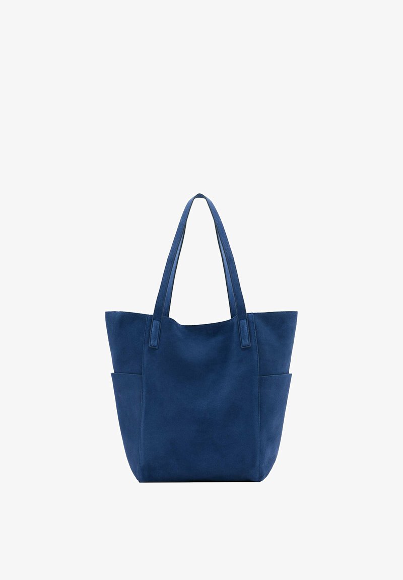 Sac fourre-tout en daim bleu avec deux bretelles et poches latérales extérieures, présenté sur fond blanc.