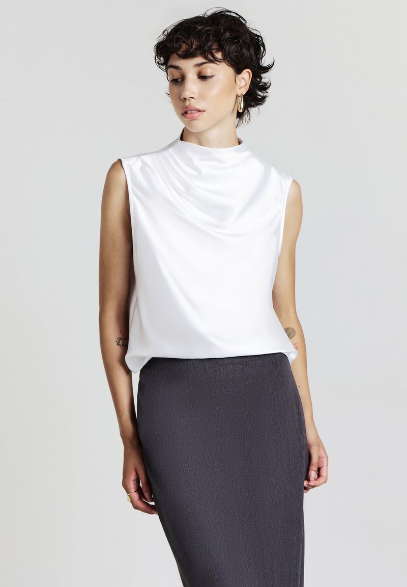 Top senza maniche in satin bianco con scollo drappeggiato, abbinato a una gonna a tubino grigia scura con texture. Design semplice ed elegante senza decorazioni.