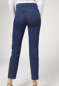 Tummansiniset farkut, joissa on korkea vyötärö, viisi taskua ja suora lahje. Kankaan pinta näyttää sileältä ja hieman joustavalta.