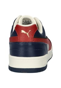 Puma sneaker met een marineblauwe en rode kleurstelling, textuur leren accenten, witte zool en gouden logo op de hiel.