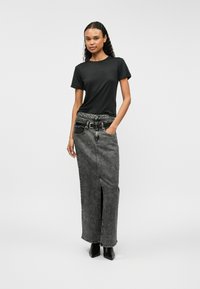 Μαύρο κοντομάνικο μπλουζάκι συνδυασμένο με μια μακριά, γκρι τζιν φούστα με πλαϊνό σκίσιμο και ζώνη στη μέση, φορεμένο με μαύρες μποτάκια μέχρι τον αστράγαλο.