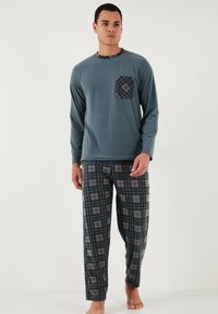 Férfi pizsama szett: hosszú ujjú teal színű felső mintás zsebbel és fekete kockás nadrággal, szürke négyzetekkel, puha anyagból és laza fazonban.