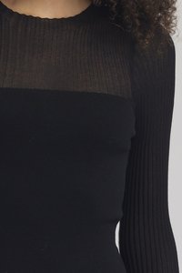 Top a coste nero con una sezione superiore trasparente e testurizzata e una parte inferiore solida. Il design è completato da un collo rotondo e maniche lunghe.