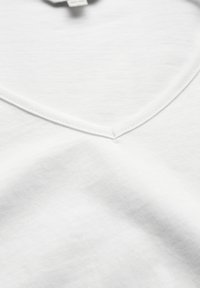 Hvid bomulds T-shirt med V-hals design; glat tekstur, fine syninger langs halsudskæringen og blød overflade detalje.