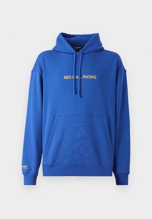 Zils džemperis ar priekšējo kangaroo kabatu, regulējamu kapuci ar auklu un "RED BULL RACING" tekstu dzeltenā krāsā uz krūtīm. Mīksta auduma.