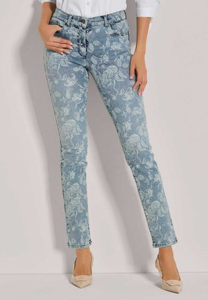 Skinny jeans in lichtblauwe denim met bloemenprint. Beschikt over vijf zakken en een knoopsluiting. Gecombineerd met beige puntige hakken.