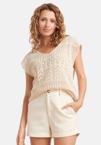 Lichtbeige gebreide top met korte mouwen, versierd met een ruitpatroon, gecombineerd met crèmekleurige textuurshorts met zijzakken.