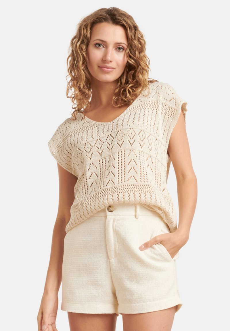 Lichtbeige gebreide top met korte mouwen, versierd met een ruitpatroon, gecombineerd met crèmekleurige textuurshorts met zijzakken.