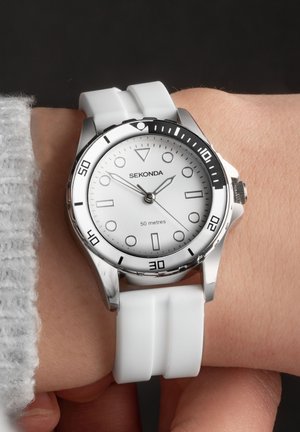 Silberner Edelstahlarmbanduhr mit weißem Zifferblatt, schwarzem Korpus und weißem Silikonarmband; verfügt über große Stundenmarkierungen und ein kleines Datumsdisplay.