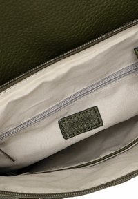 Intérieur d'un sac à main en cuir vert foncé avec une doublure beige clair, comportant une poche zippée et une étiquette estampillée "RUE 09". Texture lisse.